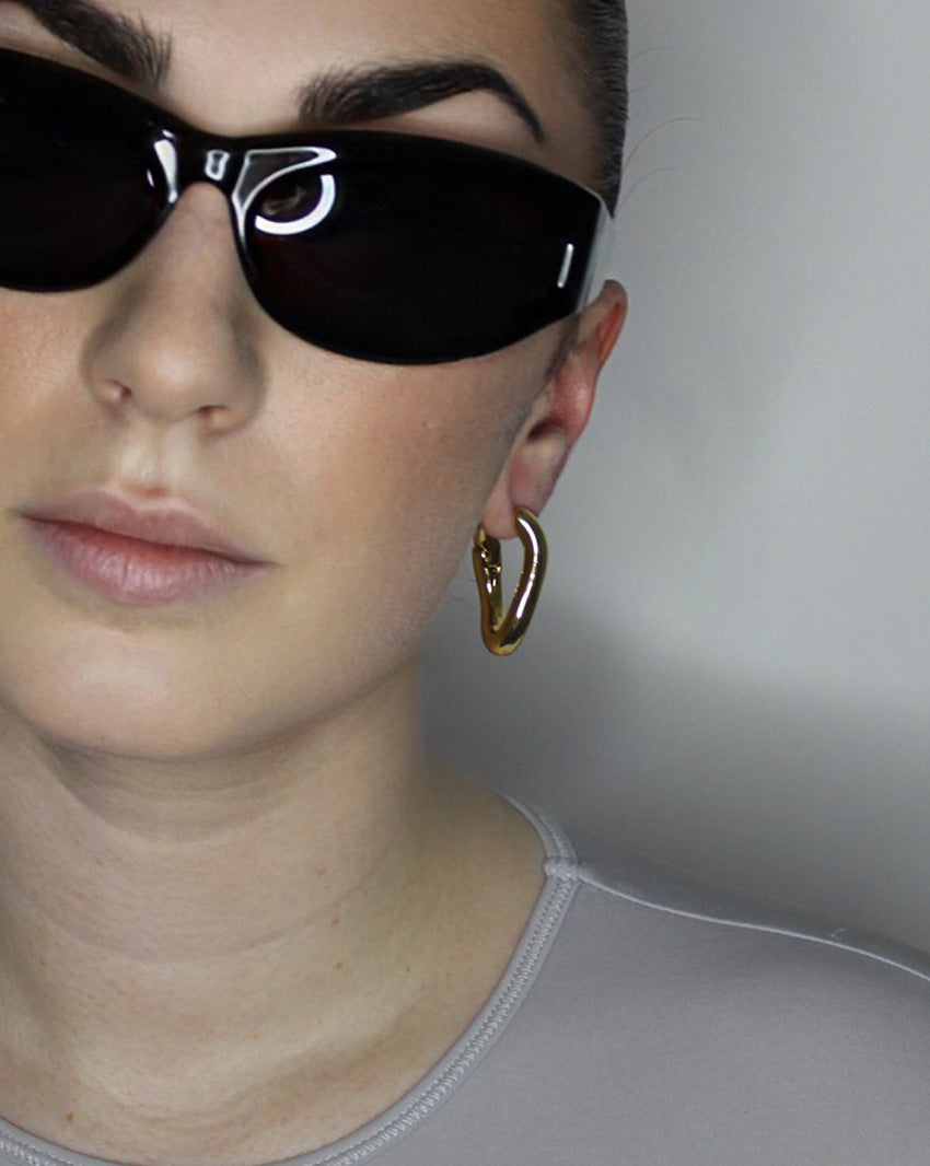 Hoop earrings in liquid twist design. 14k gold plate over recycled zinc.