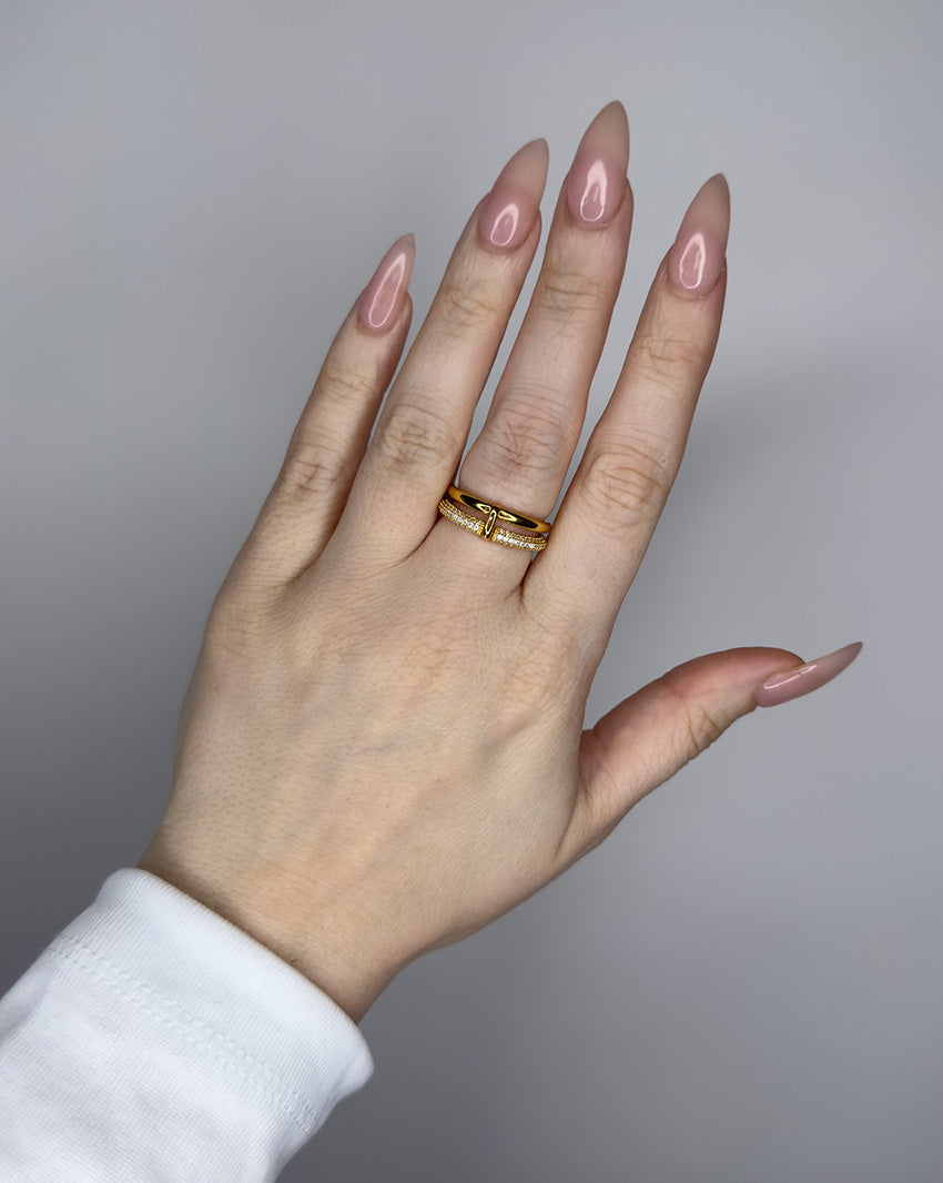 Linked ring with 2 bands linked by a connector bar. Set with imitation diamonds. 14k gold plate over recycled brass.