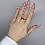 Linked ring with 2 bands linked by a connector bar. Set with imitation diamonds. 14k gold plate over recycled brass.