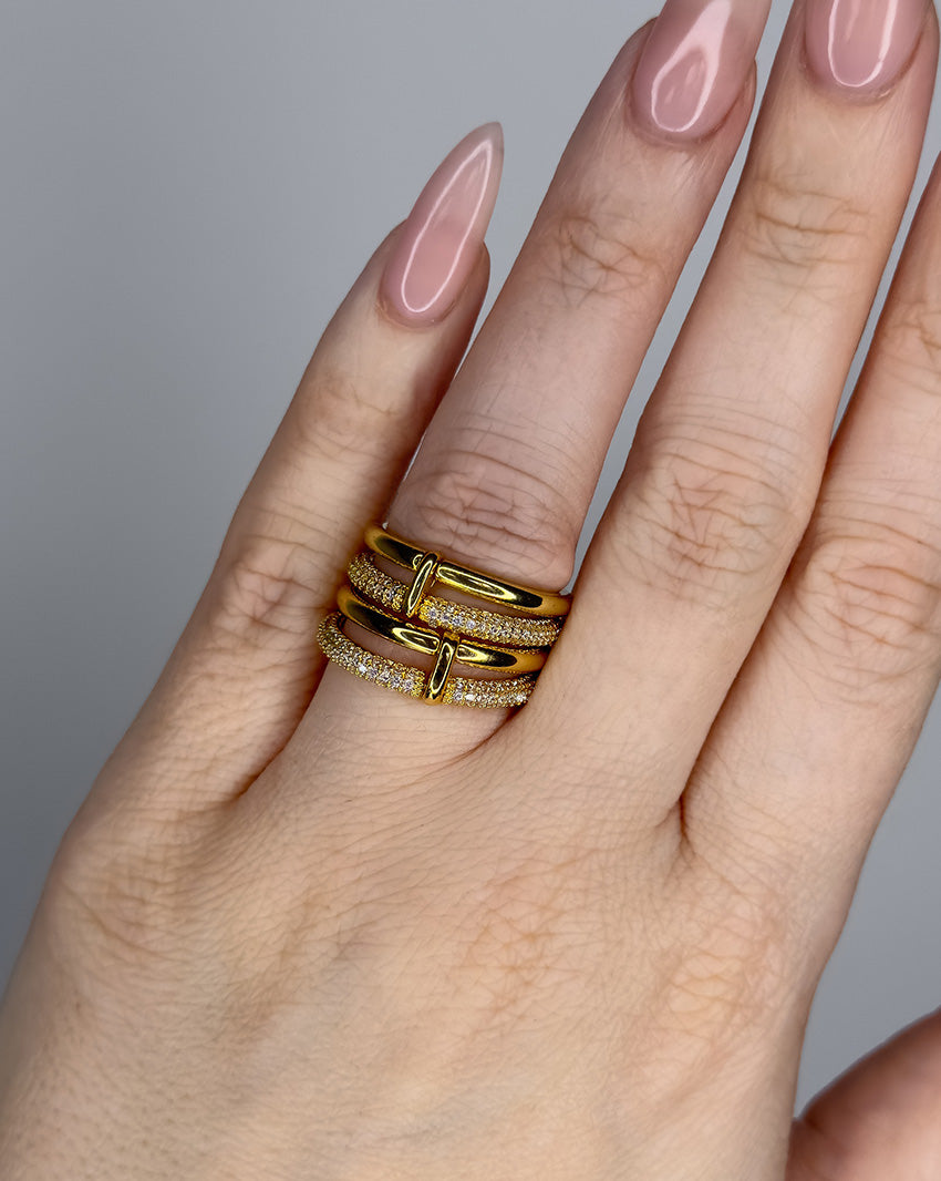 Linked ring with 2 bands linked by a connector bar. Set with imitation diamonds. 14k gold plate over recycled brass.