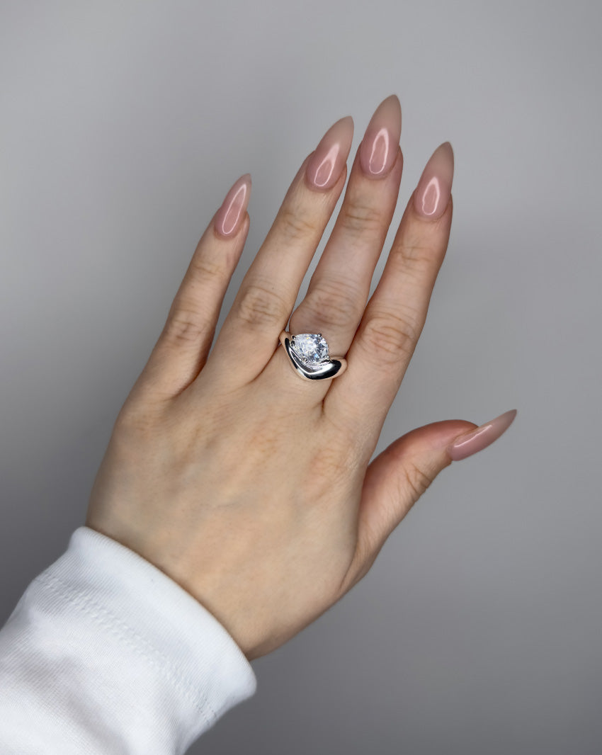 Liquid ring design with pear shape imitation diamond. Sterling silver plate over recycled brass.